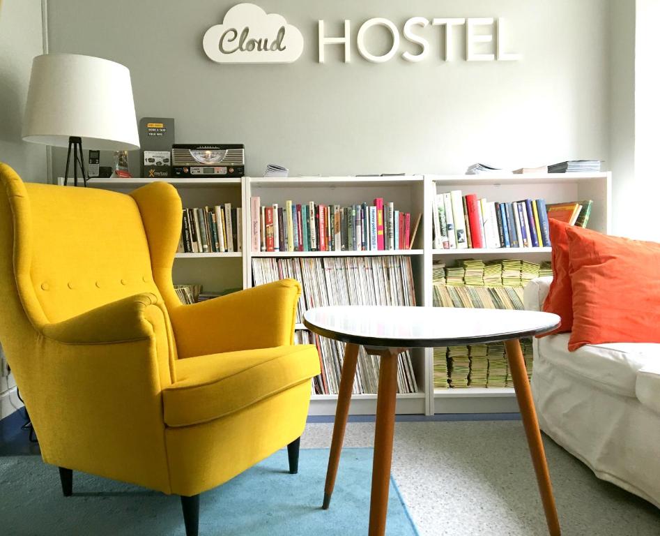 a yellow chair and a table in front of a book shelf at Cloud Hostel in Warsaw