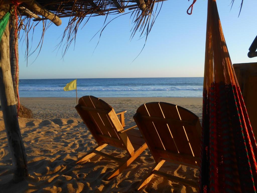 dos sillas sentadas en la arena de la playa en Cafe Maya - Casa Acalli, en Zipolite