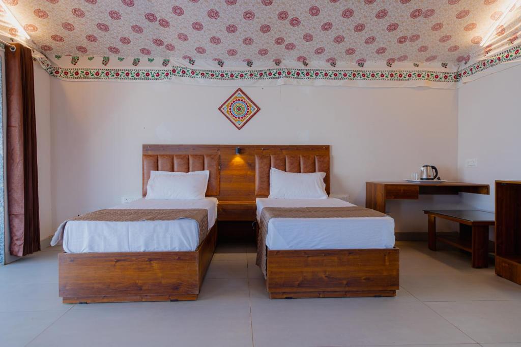 a bedroom with two beds and a table at Stayguru Road to Heaven Resort in Kunria