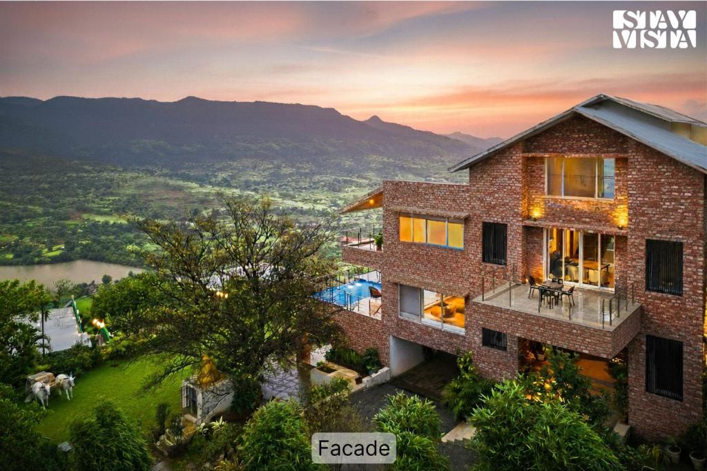 an aerial view of the villa with the sunset in the background at StayVista at Brickleaf with Pool in Malavli