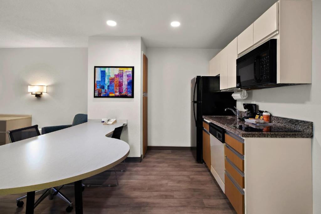 ミッドベールにあるMainStay Suites Salt Lake City Fort Unionのテーブルと冷蔵庫のある小さなキッチン