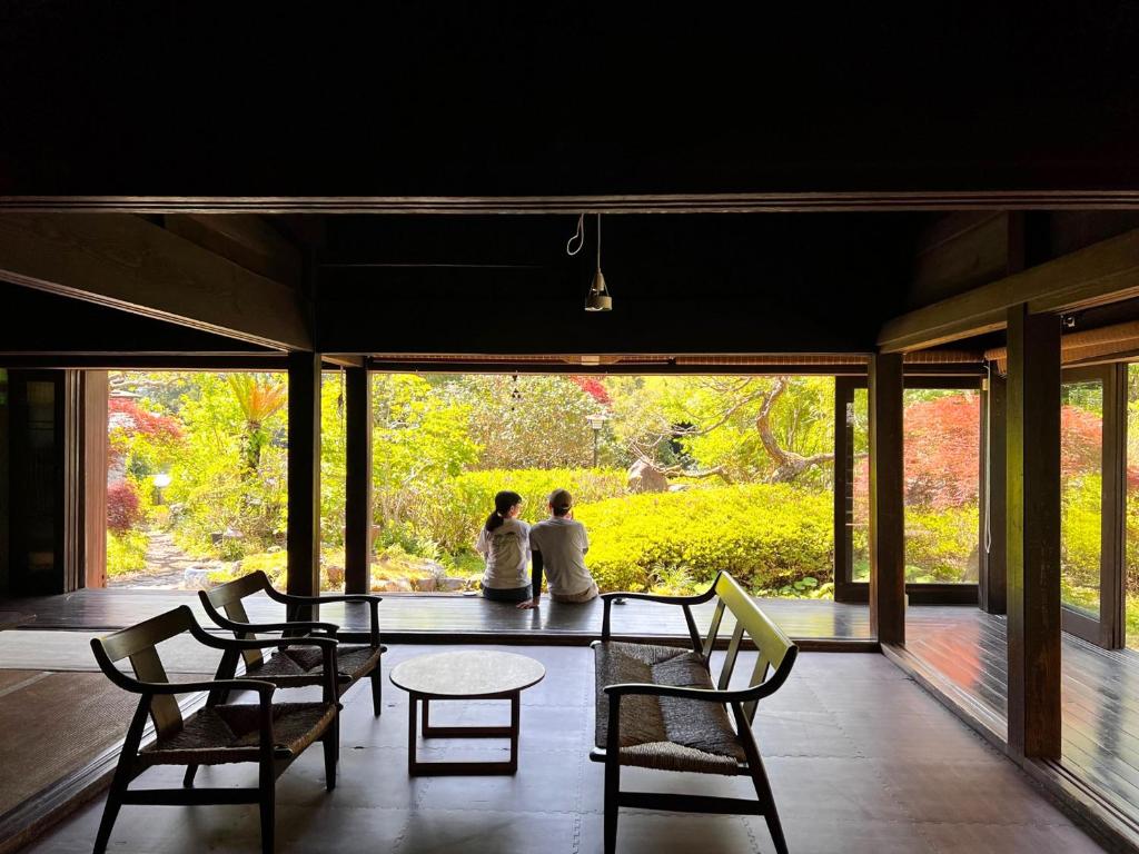 two people sitting on a table in a room with windows at 宿 にしむら Yado Nishimura Timeless Japan Experience in Shizuoka