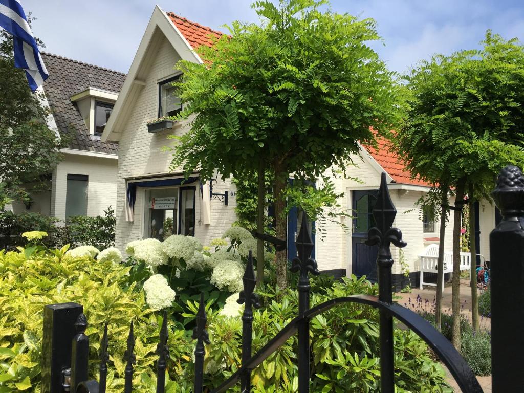 una cerca frente a una casa con flores en Pittoresque house near the beach, en Oostkapelle