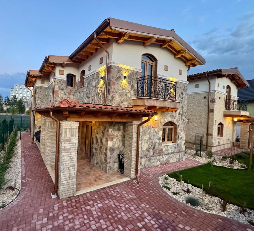 Una casa de piedra con balcón en un camino de entrada de ladrillo. en Vila Luna Brașov, en Brasov