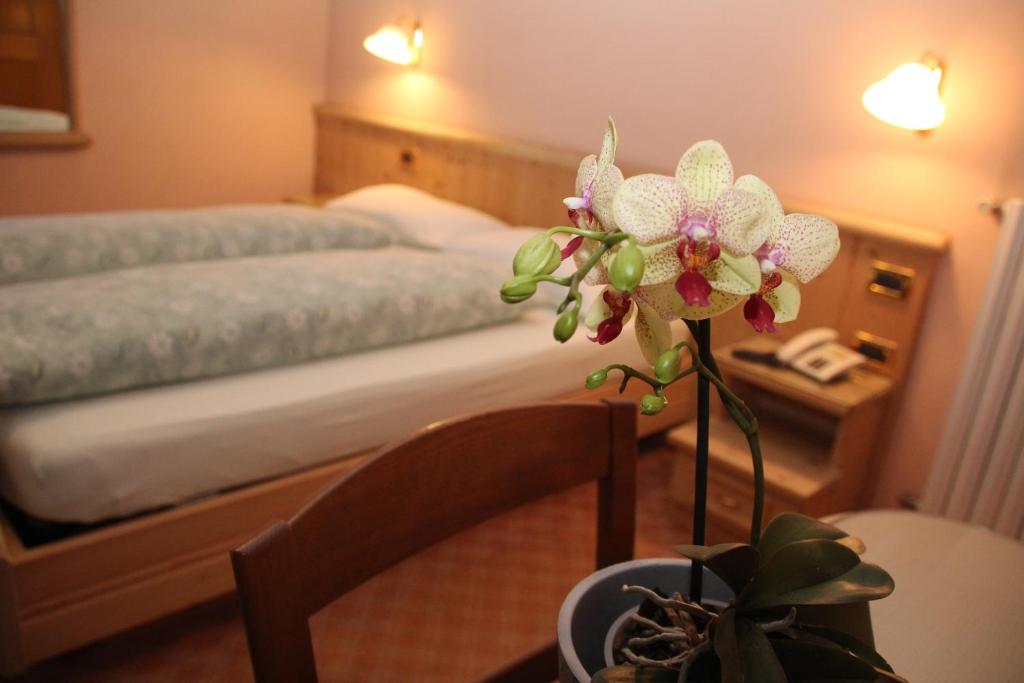 a bedroom with a bed and a table with a flower at Albergo Caravasc in Livigno