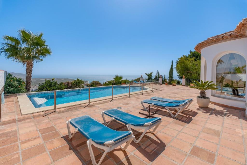 a patio with blue chairs and a swimming pool at Villa Las Brisas in Salobreña