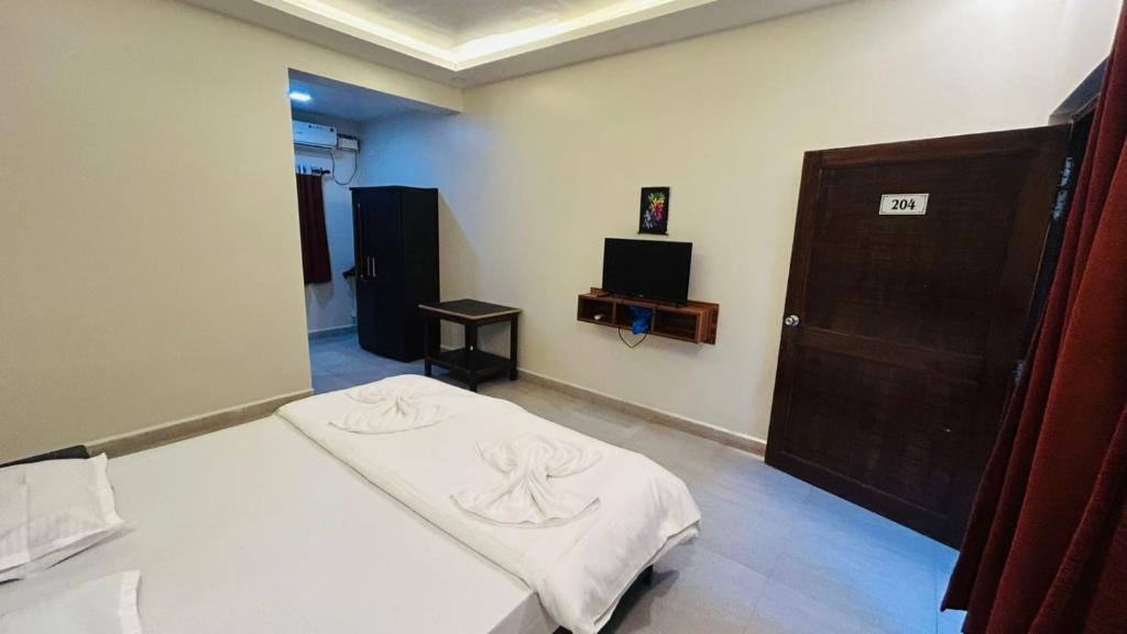 a room with a bed and a wooden door at Claudina baga beach in Calangute