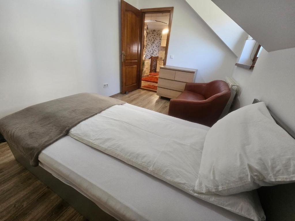 a bedroom with a bed and a chair in it at Flower Apartment Cintia in Odorheiu Secuiesc