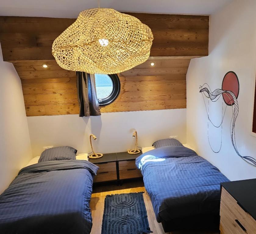 due letti in una stanza con un lampadario di La Péniche - Gîte de groupe insolite a Saint-Omer