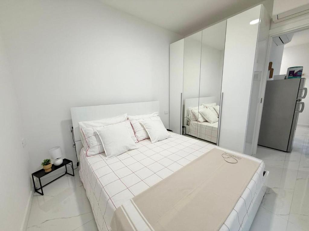 ein weißes Schlafzimmer mit einem großen weißen Bett mit Kissen in der Unterkunft Charm Home Alassio in Alassio