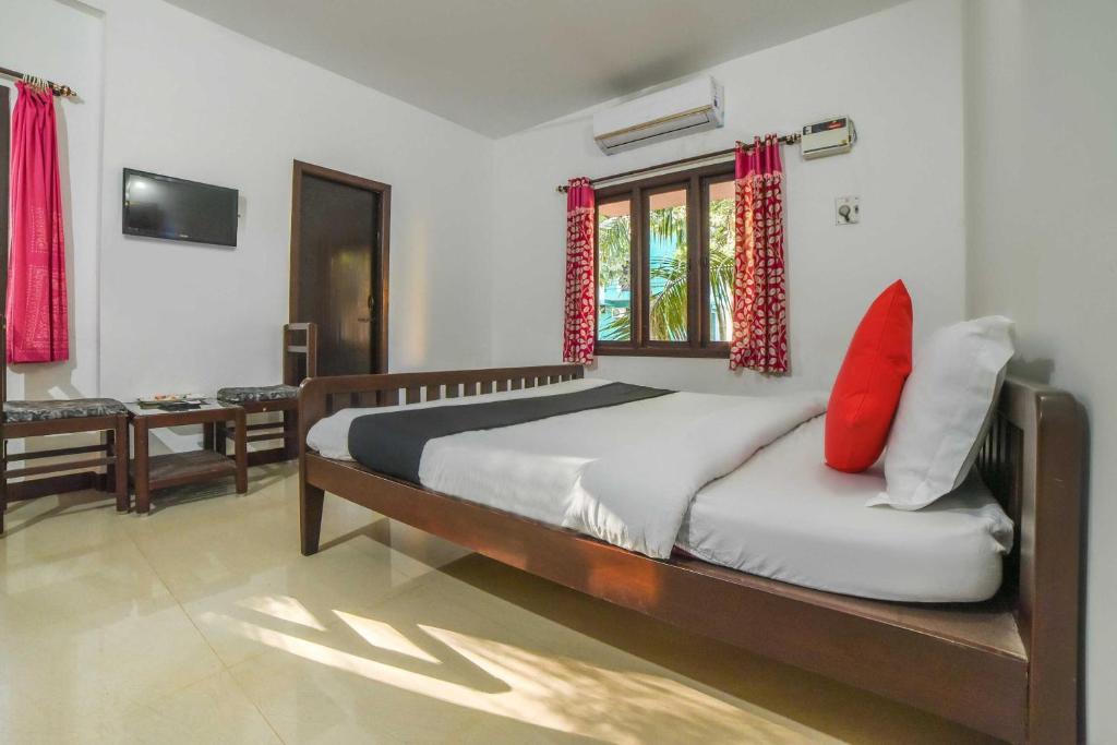 a bedroom with a large bed with red pillows at Hotel O Auroville Beach Formerly Prince Park Garden in Kuilapayam