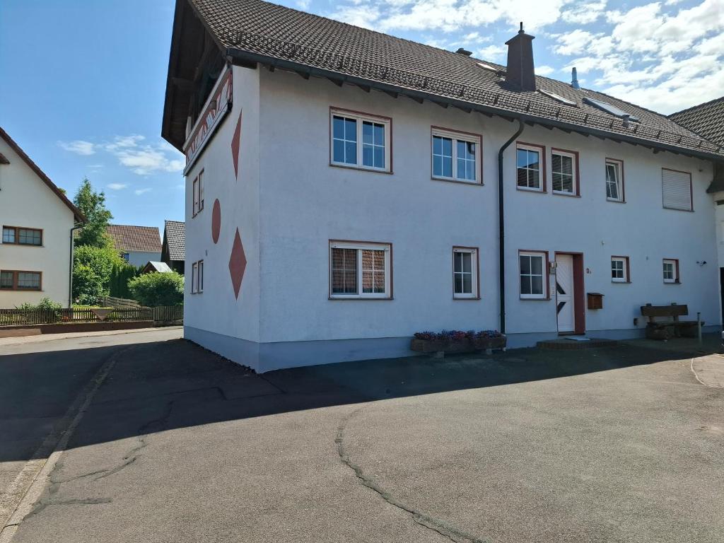 a white house with a black roof on a street at Ferienwohnung Schönhals in Hochwaldhausen