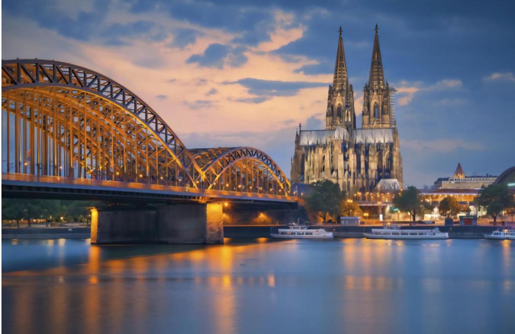 a bridge over the water with a cathedral and a church at Zentrales Apartment nähe Dom 5 Haltestellen bis Kölnmesse in Cologne