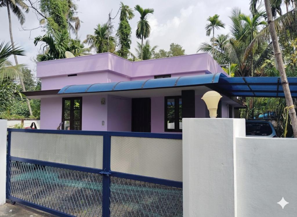 a pink house with a blue roof behind a fence at Chillout home stay in Ernakulam