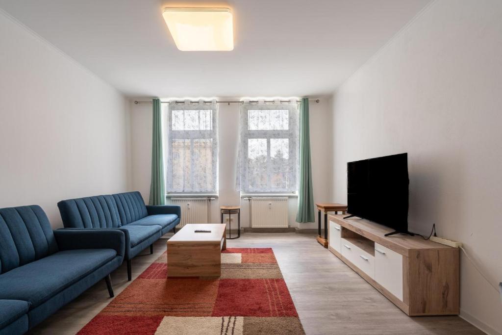 a living room with two blue couches and a flat screen tv at Theater Apartment in Gera