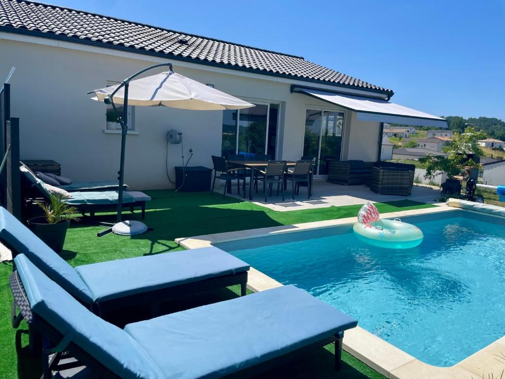 a backyard with a swimming pool and an umbrella at villa Emilie in Trélissac
