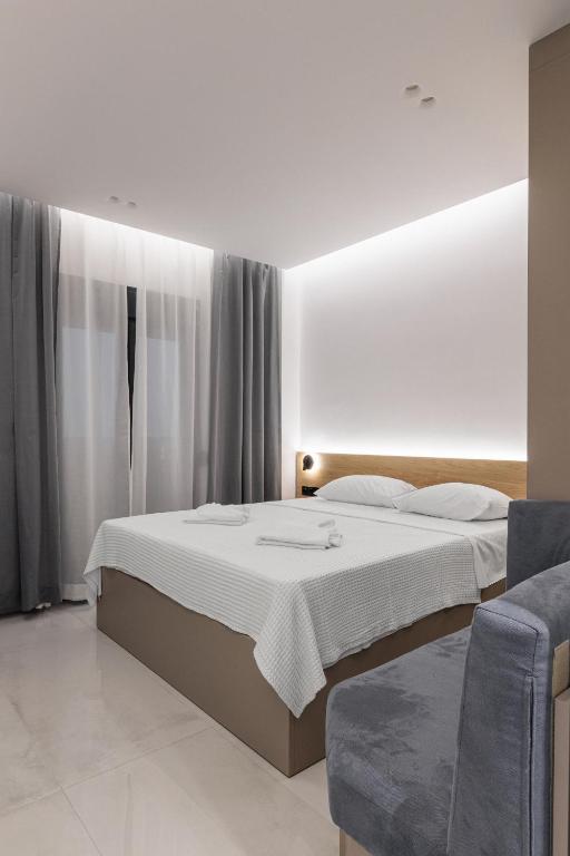 a white bedroom with a bed and a couch at Dialetti's Nook In Ελλάδα in Thessaloniki