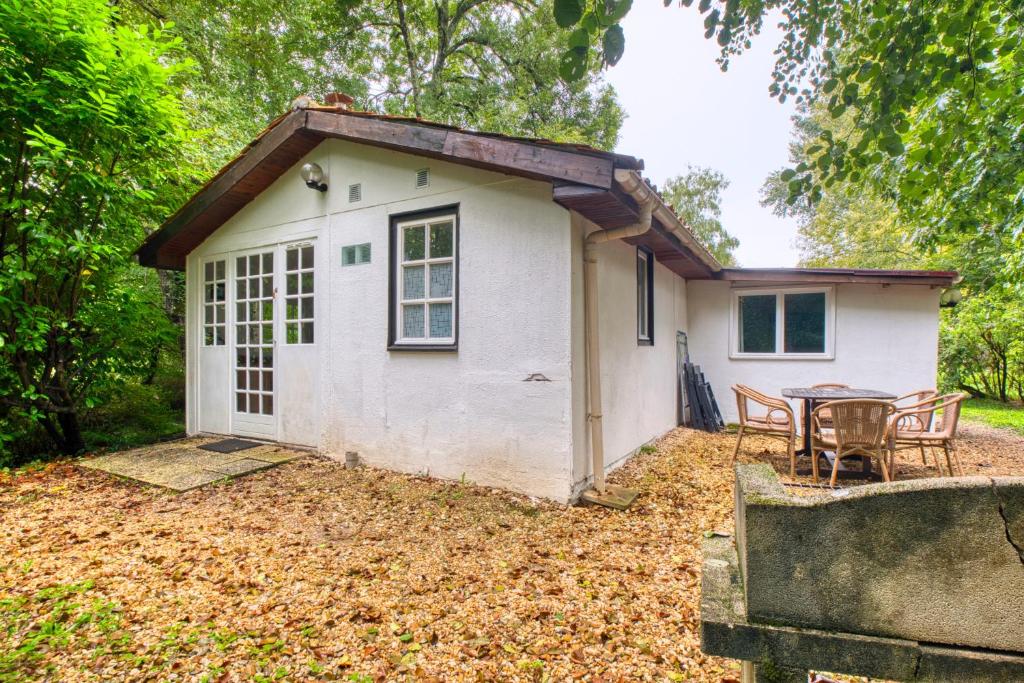 a small white house with chairs and a table at Gite Le Martin Pecheur in Varaignes