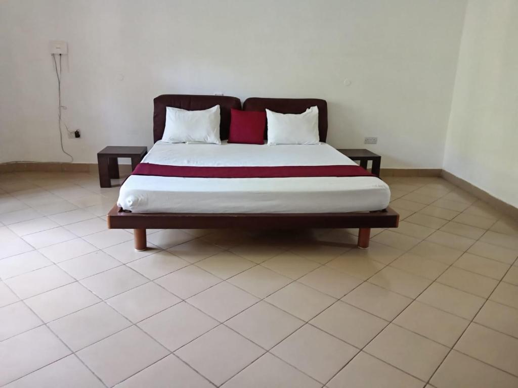 a bed with two red pillows on it in a room at Kk bnb in Mombasa