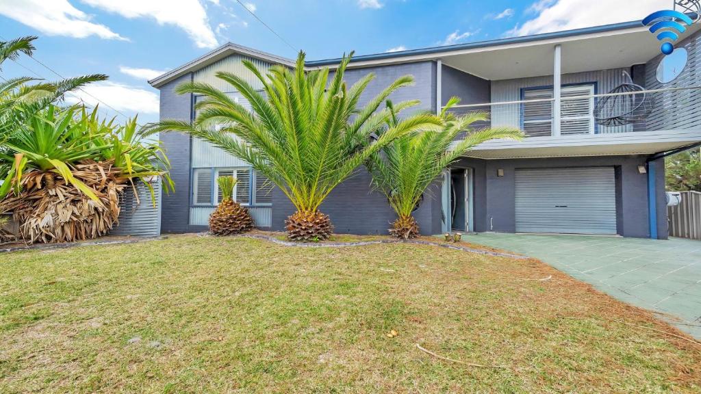 a house with two palm trees in front of it at Seaside Royale in Callala Beach