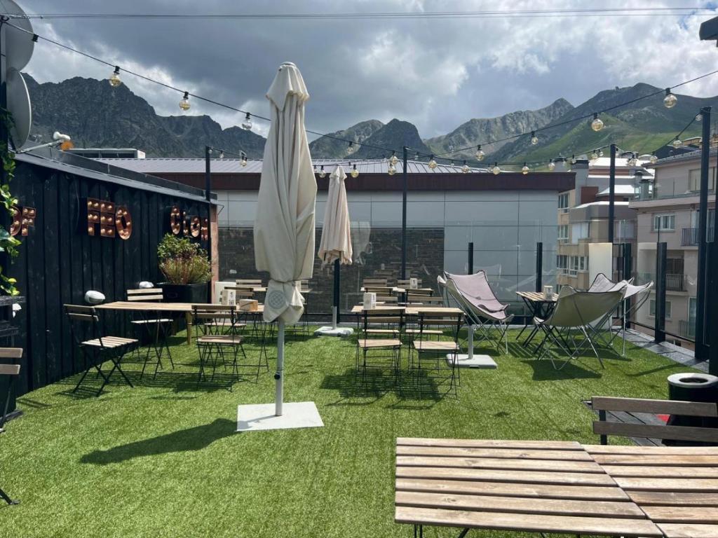 a patio with tables and chairs and an umbrella at Hotel KATHMANDU - PANDA in Pas de la Casa