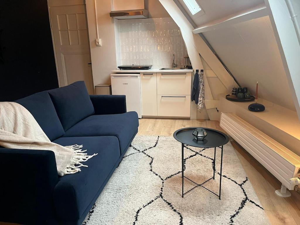 a living room with a blue couch and a table at Cozy apartment in Enschede