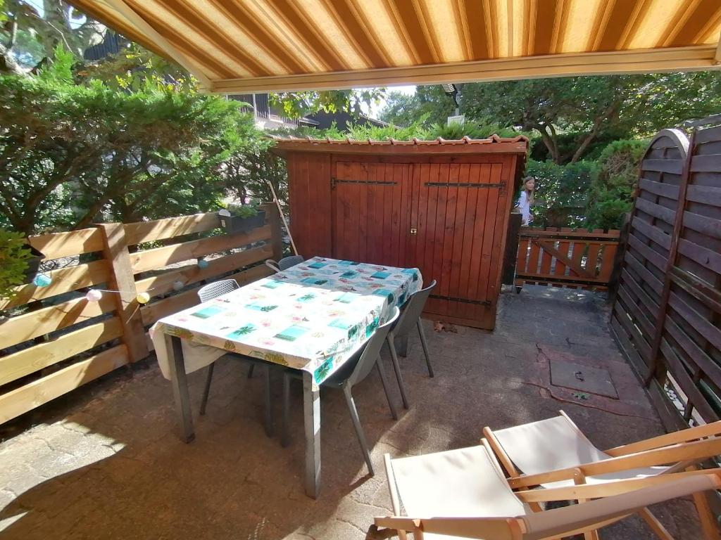 ein Tisch und Stühle auf einer Terrasse mit einer Bank in der Unterkunft Maison entre lac et océan WIFI in Lacanau