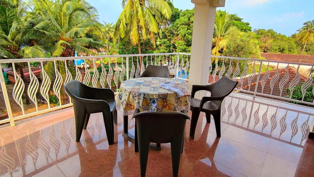 a table and chairs on a balcony with palm trees at ArtCove Goa in Siolim