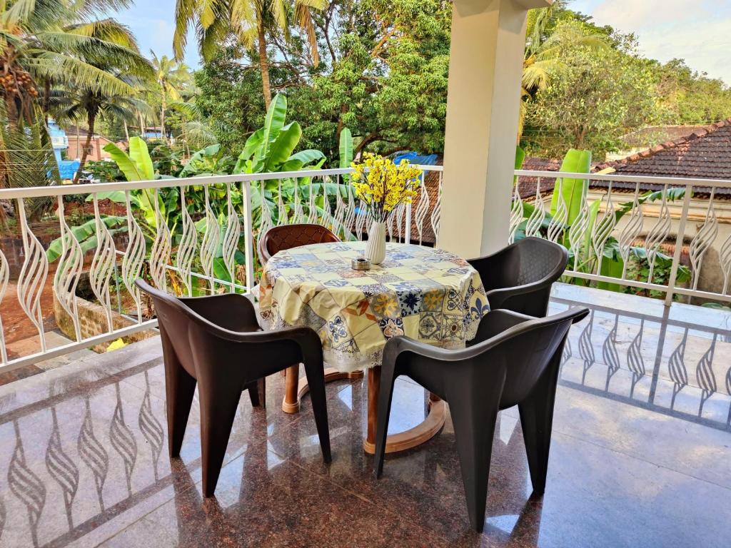 a table with chairs and a vase of flowers on a balcony at ArtCove Goa in Siolim