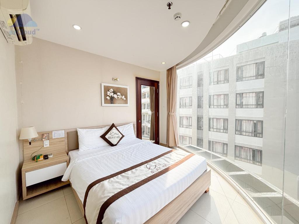 a bedroom with a bed and a large window at Bella VT Hotel - Bãi Sau Vũng Tàu in Vung Tau