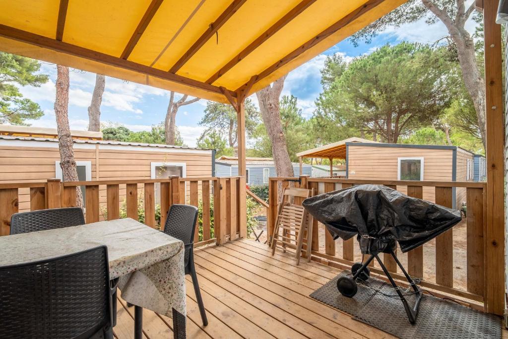 een patio met een tafel en stoelen op een houten terras bij Mobilhome au Camping La Yole in Vendres-Plage