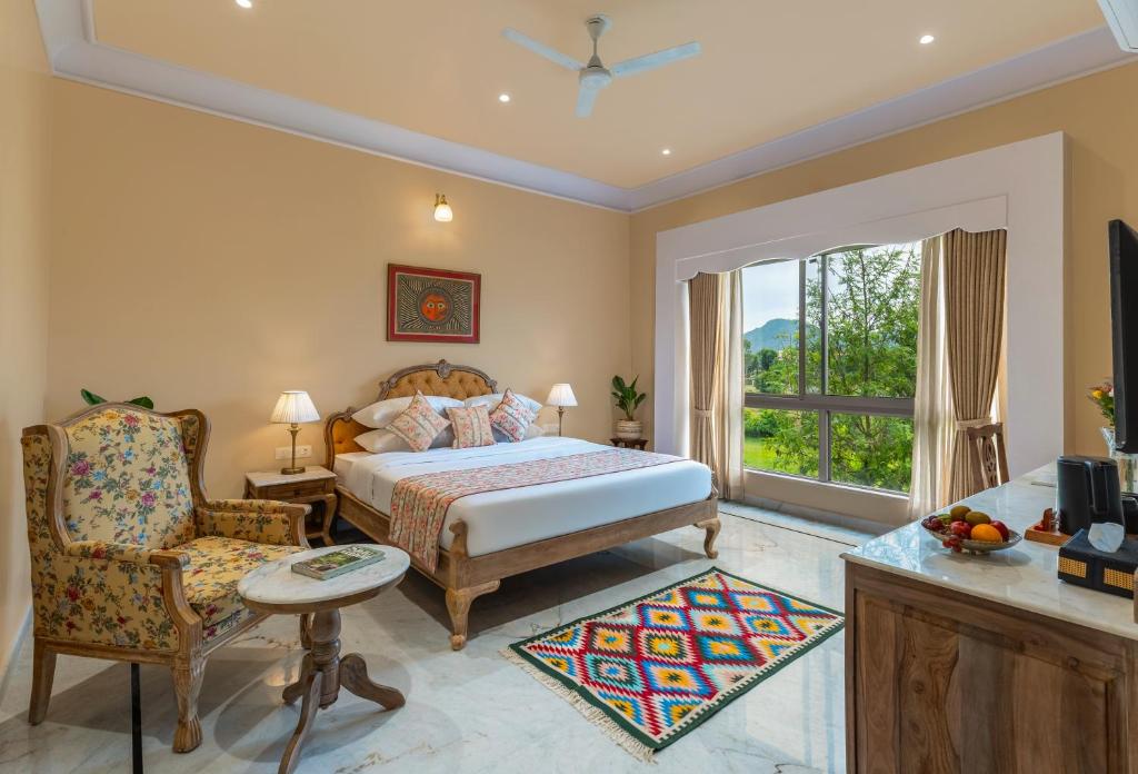 a bedroom with a bed and a chair and a window at Dilip Niwas Luxe Stay - Near Fateh Sagar Lake 2 KM in Udaipur