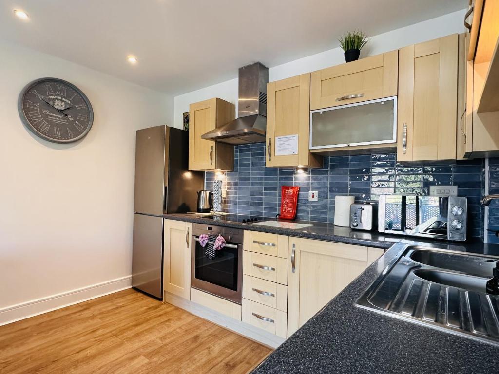 a kitchen with wooden cabinets and a clock on the wall at Grand Central Apartments in Derby