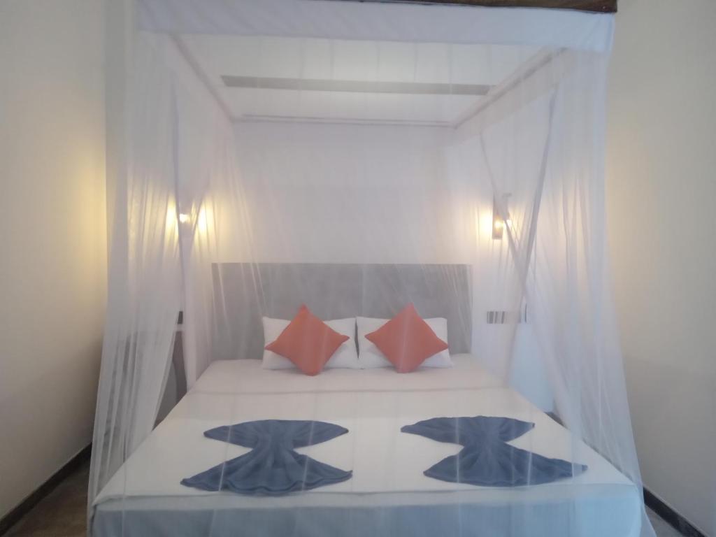 a bedroom with a bed with red and blue pillows at Danu Surf House Hiriketiya in Dickwella