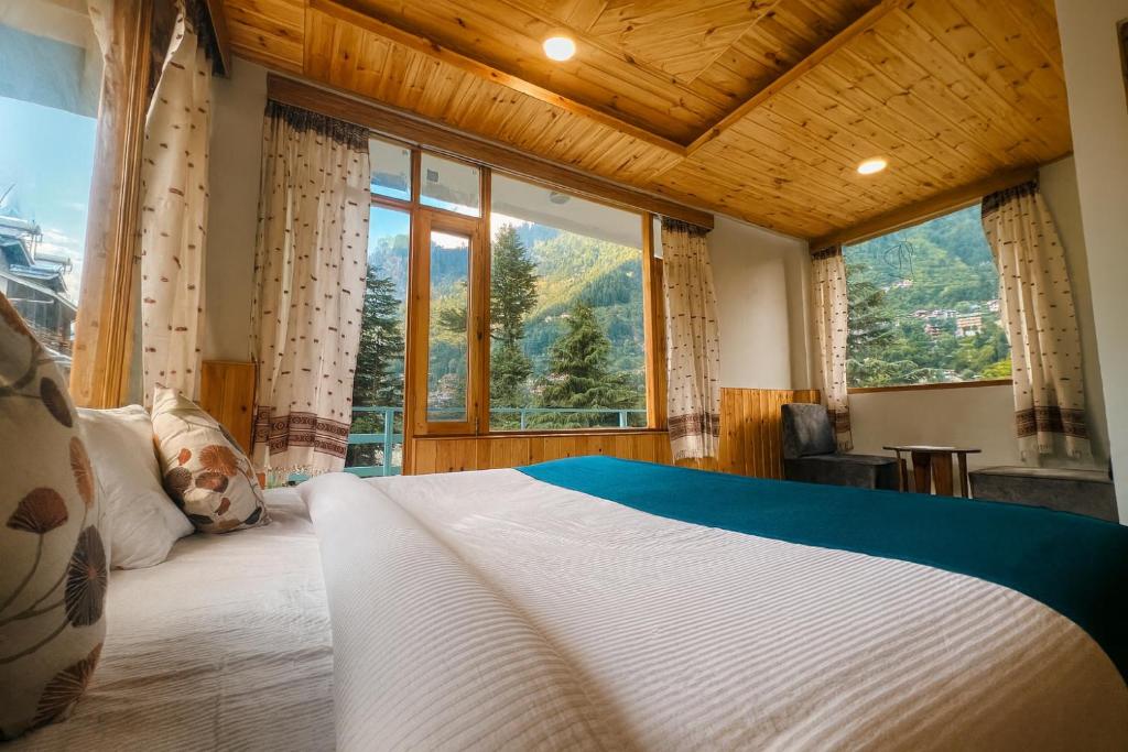 a bedroom with a large bed and a large window at Apple Flower Himalayan Heights - Luxury Stay with Mountain Views, Parking & Garden in Manāli