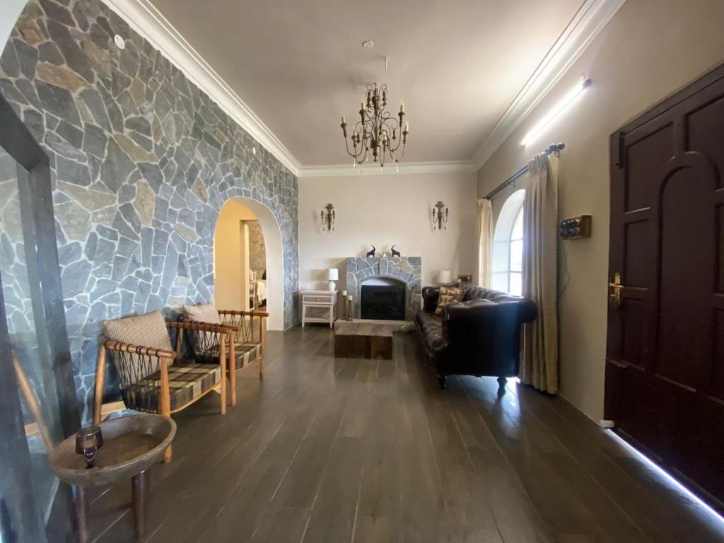 a living room with a fireplace and a stone wall at Cold Stone Villa -a cozy escape above the clouds in Kodaikānāl