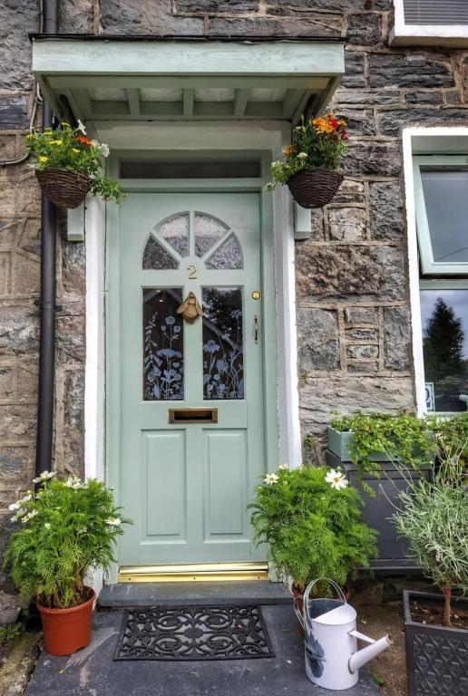 a blue door on a stone house with potted plants at Waterfall retreat in Blaenau-Ffestiniog