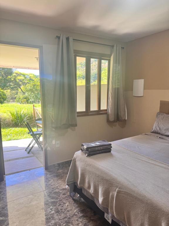 a bedroom with a bed and a window and a patio at Serra Mar à beira rio , rafting, suites, lofts, e Casas in Sana