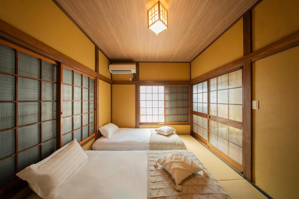 two beds in a room with two windows at 日本の生活を体験できる古民家 一棟貸切最大7名 jr上中里駅 in Tokyo