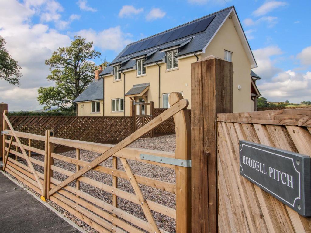 a house with a wooden gate and a sign at Hoddell Pitch Cottage in Kinnerton
