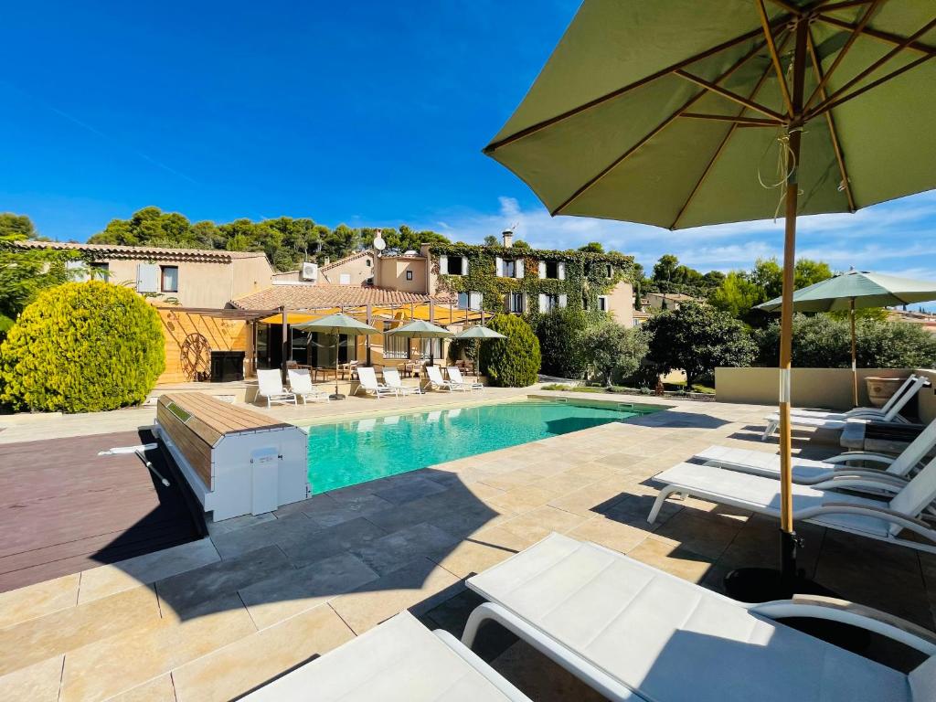 a swimming pool with chairs and an umbrella at La Réserve Provence in Vaugines