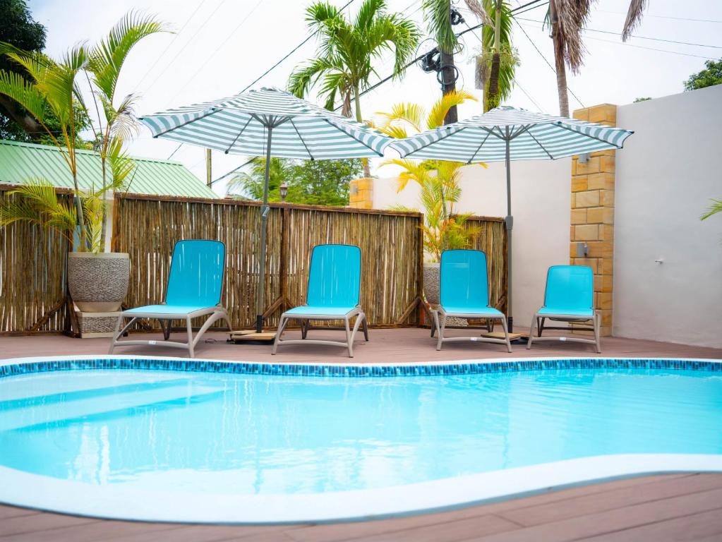 una piscina con sillas y sombrillas azules en Ocean Cove, en Anse aux Pins