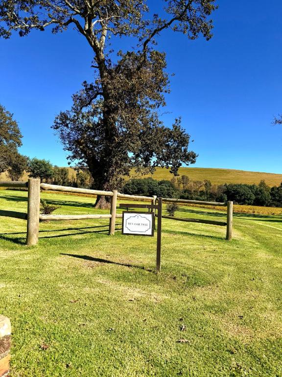 a sign on a fence in a field with a tree at Treeferns Trout Lodge in Dullstroom