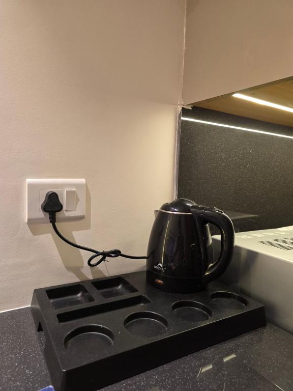 a black tea kettle sitting on top of a stove at Easy Stayz - Premium stays in Greater Noida in Greater Noida