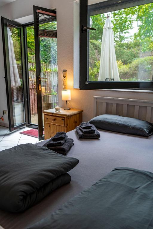 two beds in a room with a large window at Studio mit Terrasse bei Frankfurt in Bad Vilbel