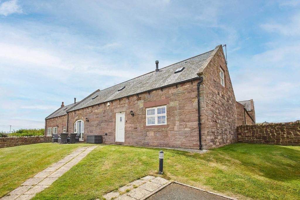 un vieux bâtiment en briques avec une cour gazonnée dans l'établissement Host & Stay - Dolphin Dream, à Beal