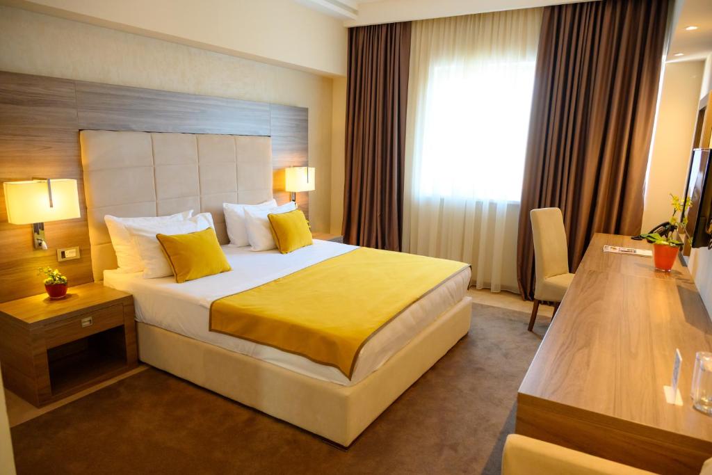 a hotel room with a large bed with yellow pillows at Hotel Tami Residence in Niš