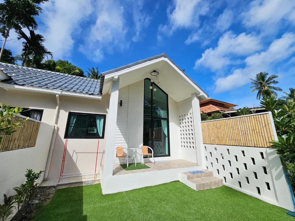 a white house with a green lawn at Srithanu Haus in Haad Chao Phao