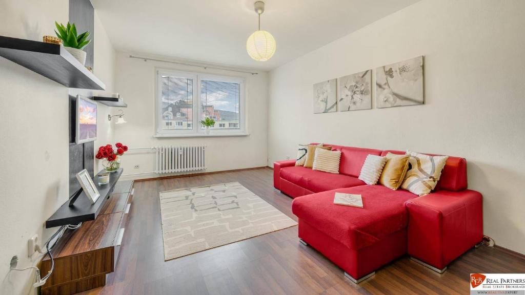 a living room with a red couch and a table at Tichý apartmán Dúbravka in Petržalka