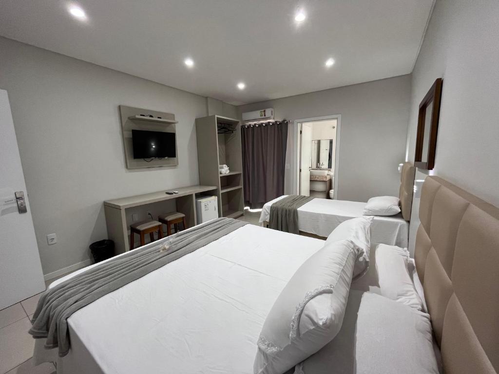 a hotel room with two beds and a tv at Pousada Bela By Bia - Comfort in Penha